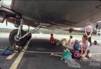 Passengers sitting in the shade of an Air Queensland DC3, Lockhart Airport, 1982